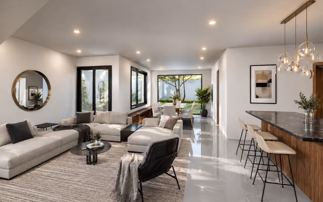 Render interior de una sala abierta con comedor, barra de cocina y vista al jardín