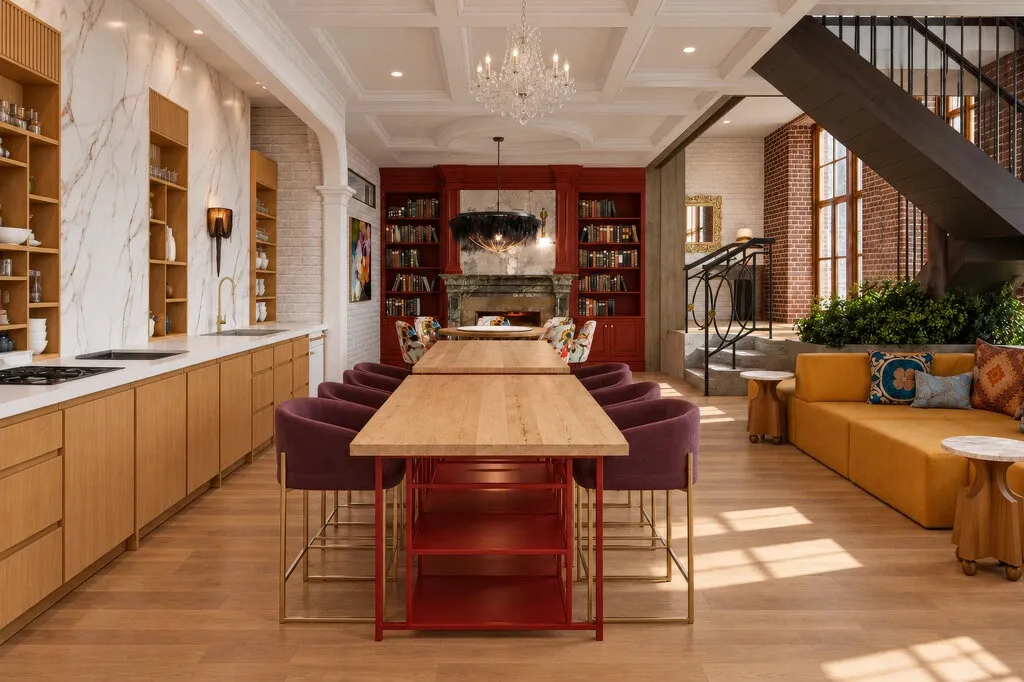 Render de un espacio común con cocina, mesa larga, librero rojo y sala, obra de Maverick Frame